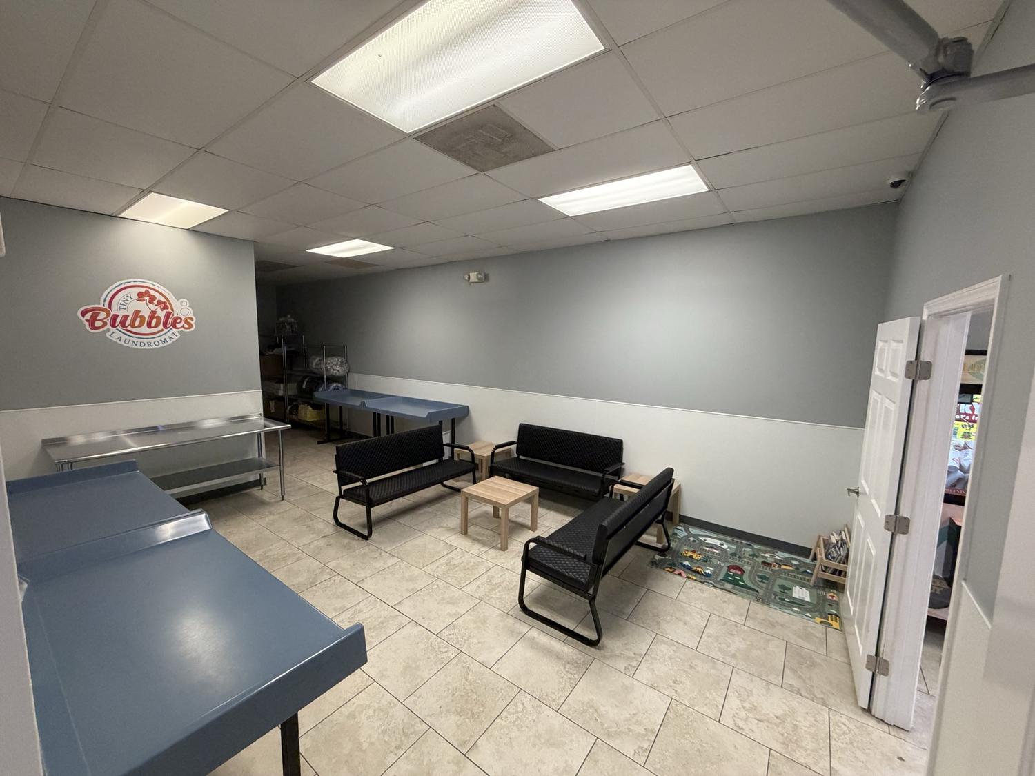 The customer lounge at Tiny Bubbles Manassas, with seating, a kids area and the Tiny Bubbles logo painted on the wall